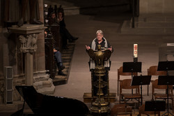Das Bild zeigt eine männlich gelesene Person am Rednerpult in einer Kirche.