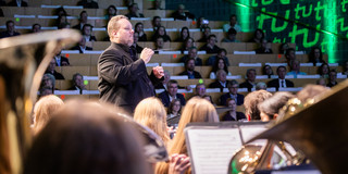 Der Dirigent des Sinfonischen Blasorchesters, Constantin Hesselmann, dirigiert das Orchester während eines Konzertes.