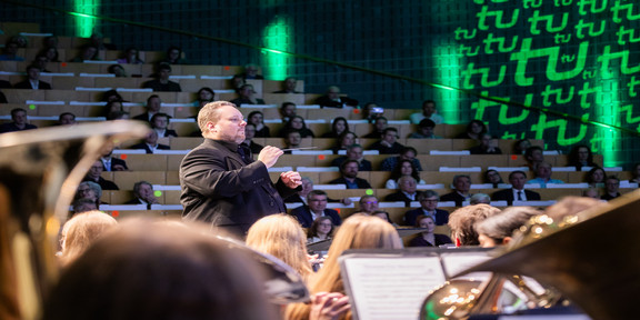 Der Dirigent des Sinfonischen Blasorchesters, Constantin Hesselmann, dirigiert das Orchester während eines Konzertes.