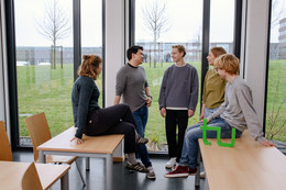 Kontakt Ein Gruppenfoto von Studierenden im Seminarraum mit dem TU Dortmund Logo. Sie sprechen miteinander und schauen sich an.